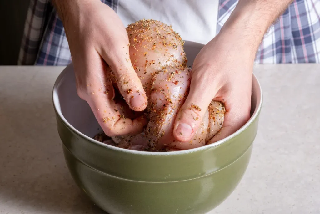 raw chicken with Buffalo Chicken Dry Rub in a green mixing bowl.