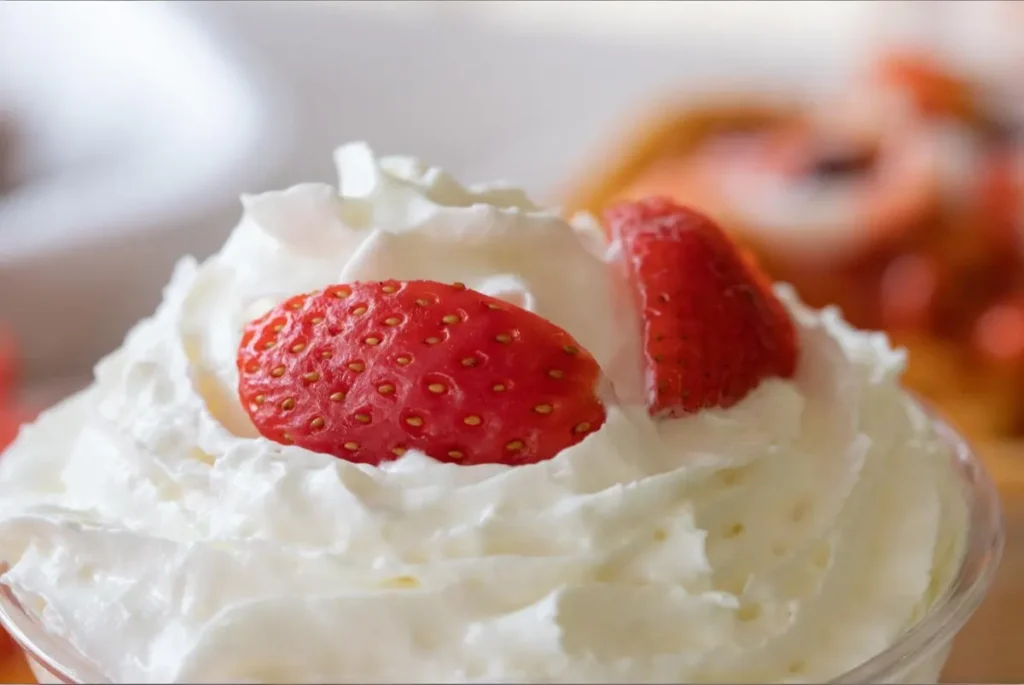 A close-up of whipped topping with fresh strawberry slices on top.